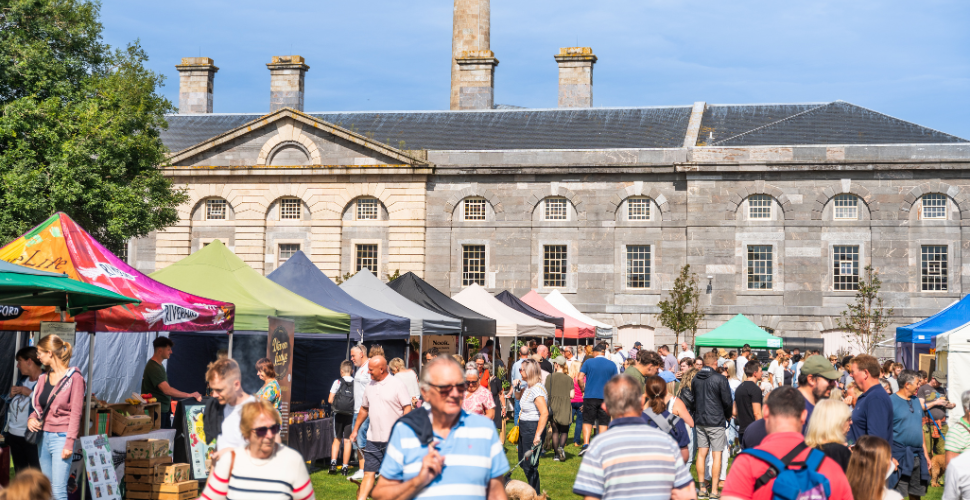 An outside market with people walking through it in the sun